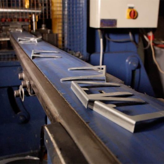 Pressed metal components on conveyor at Crossen Engineering, UK.